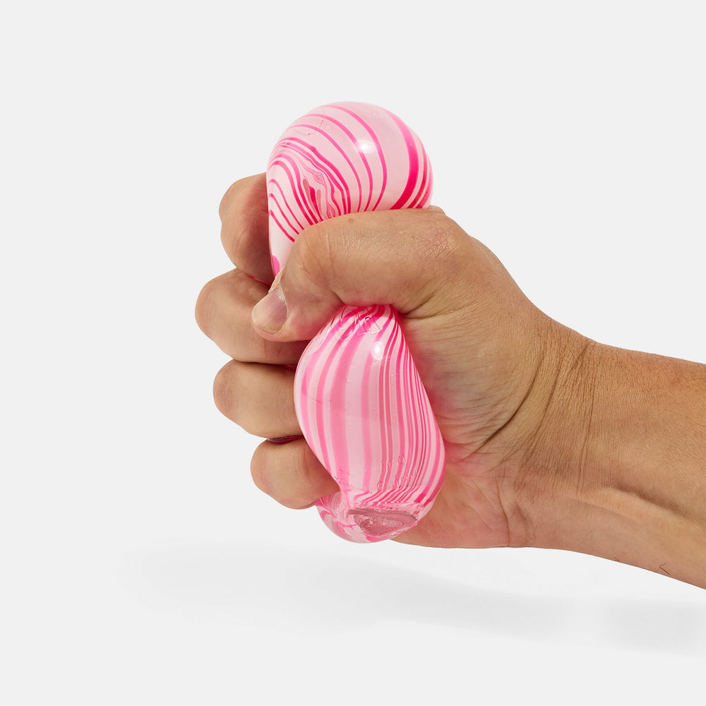 A hand squeezing a pink and white marbled, squishy stress ball against a clean white background.