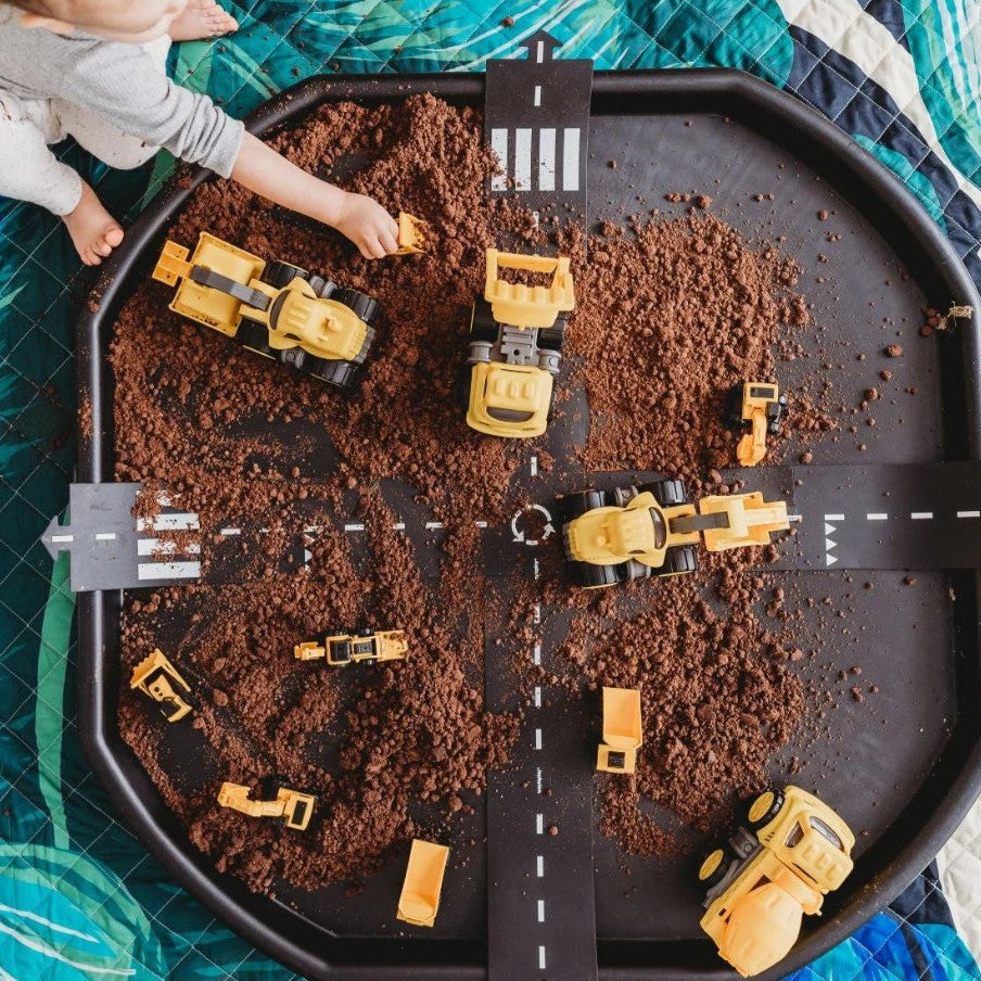 Children's toy construction set on a tray with sand and road markings