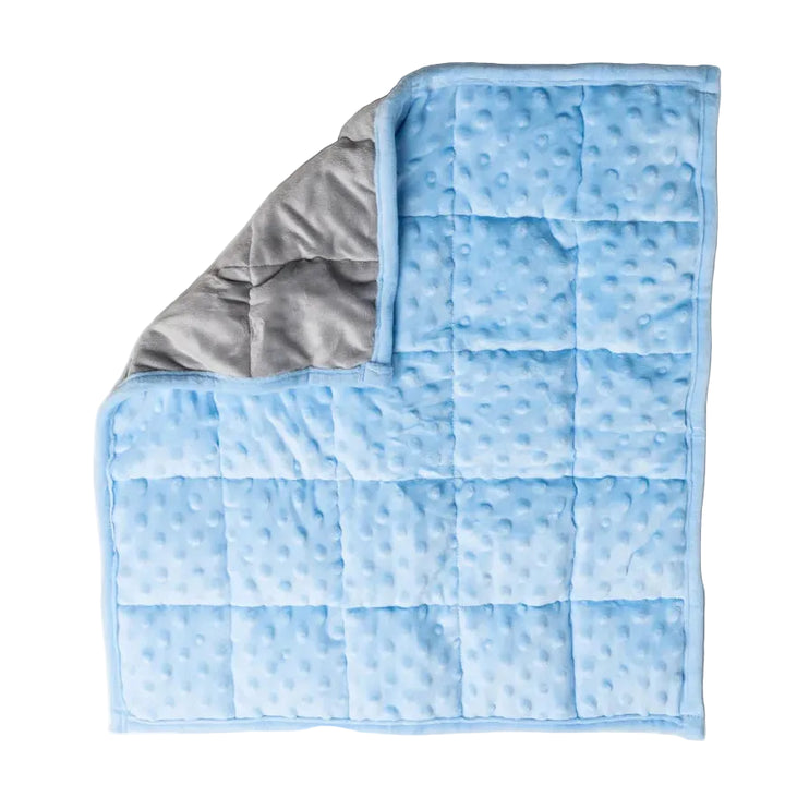 A light blue weighted lap blanket with a textured minky fabric cover and a soft gray fleece lining, shown folded on a white background.